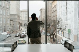 Profesional expatriado mirando por la ventana de su oficina durante una llamada, contexto habitual del burnout en la población expatriada en Madrid