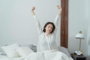 Mujer adulta despertándose en la cama con luz natural matutina, ilustrando la sensación de cansancio y sueño no reparador típica del insomnio crónico