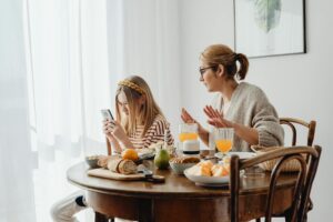 Mother talking with her adolescent daughter about phone use, illustrating the family conversation around social media and screens at home