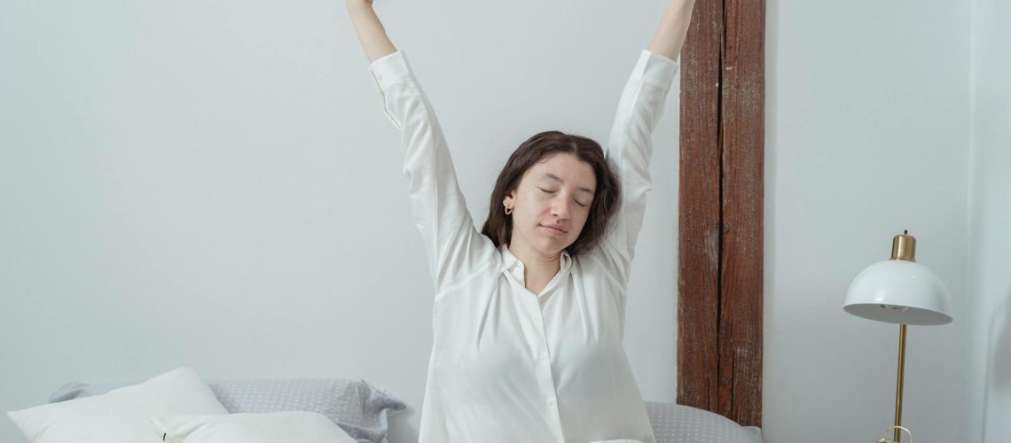 Mujer adulta despertándose en la cama con luz natural matutina, ilustrando la sensación de cansancio y sueño no reparador típica del insomnio crónico