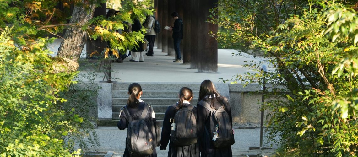 Tres niños caminando hacia un colegio, contexto escolar habitual de la evaluación y el tratamiento del TDAH en la infancia y adolescencia